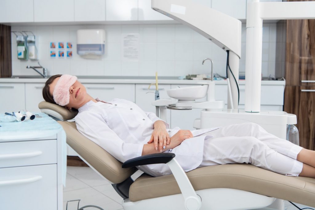 A woman with a sleep mask in a dentist chair.