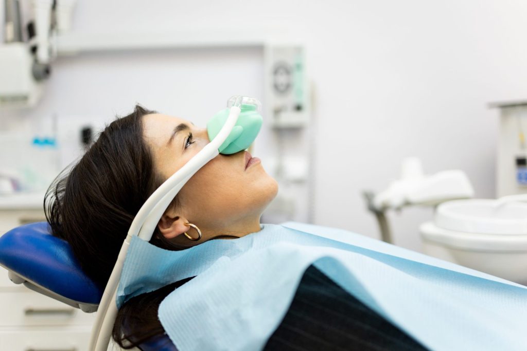 Woman in the dental chair breathing nitrous oxide through a nose mask