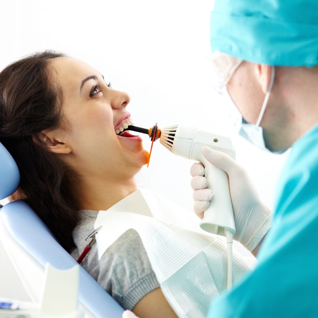Dentist using a curing light on a smiling patient's filling