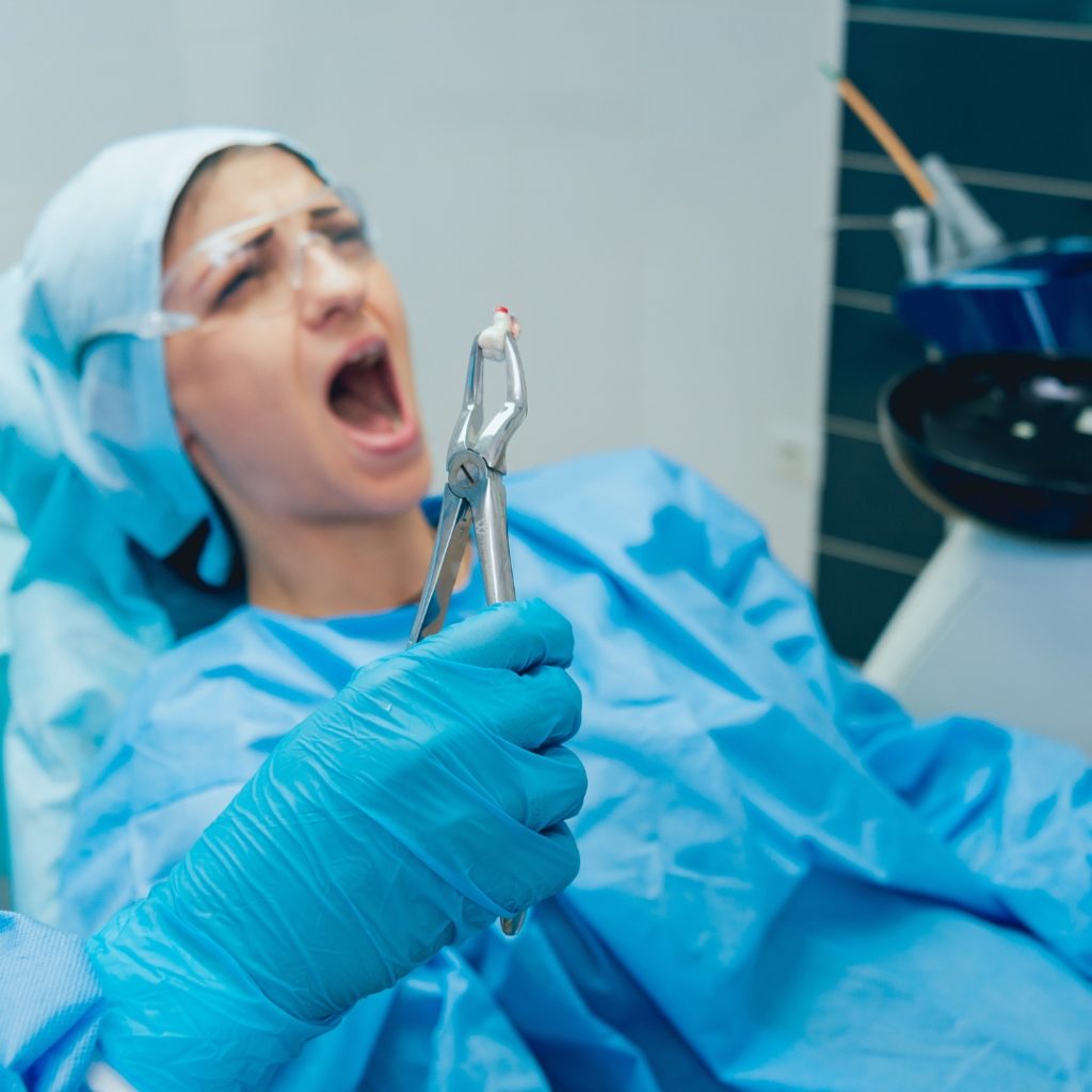 Dentist holding extraction forceps beside a patient