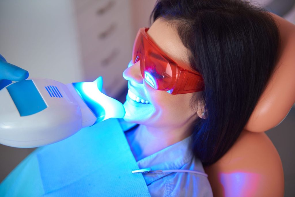 Woman having in-office teeth whitening with a blue light