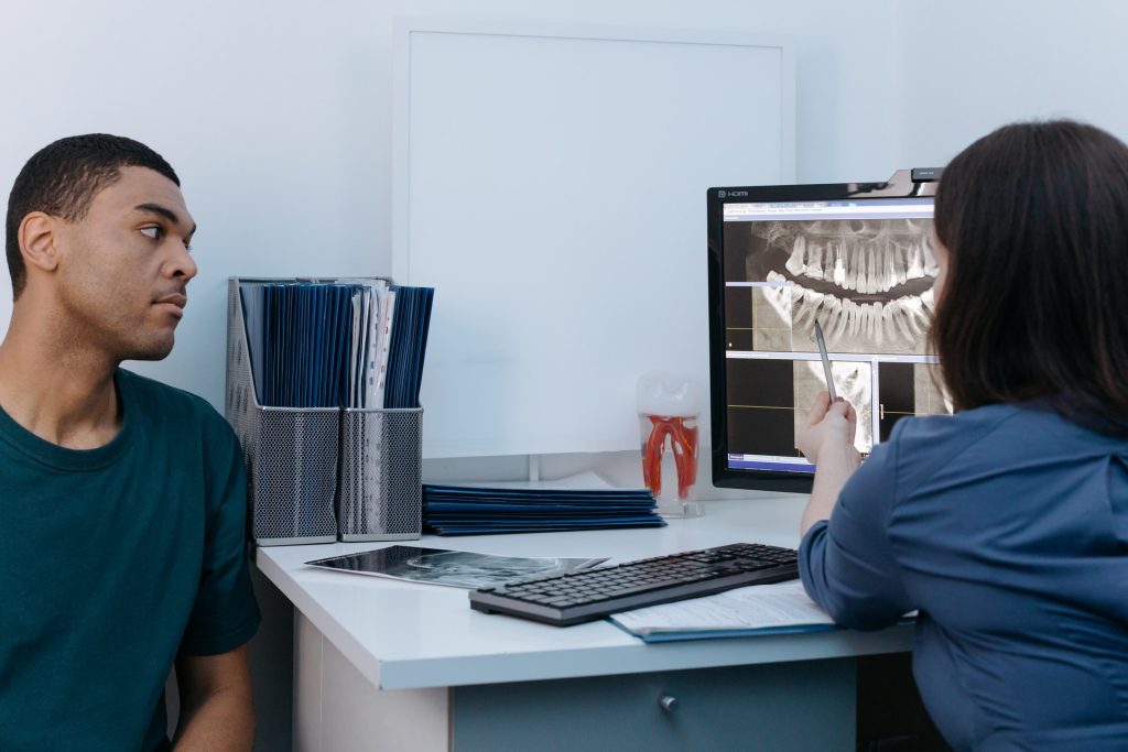 Dentist showing a patient a dental X-ray on a screen